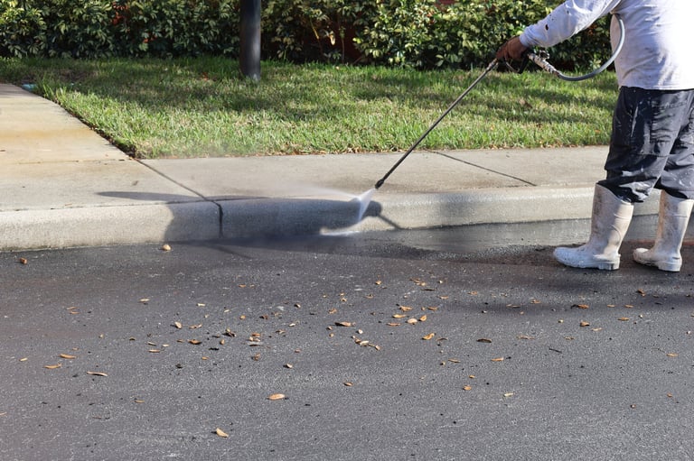 Worker cleaning pavement with high pressure washer. Outdoor maintenance and cleaning service concept.